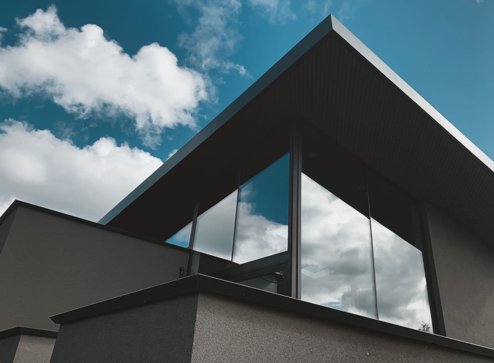 Moderne aanbouw met glazen gevel tegen een blauwe lucht